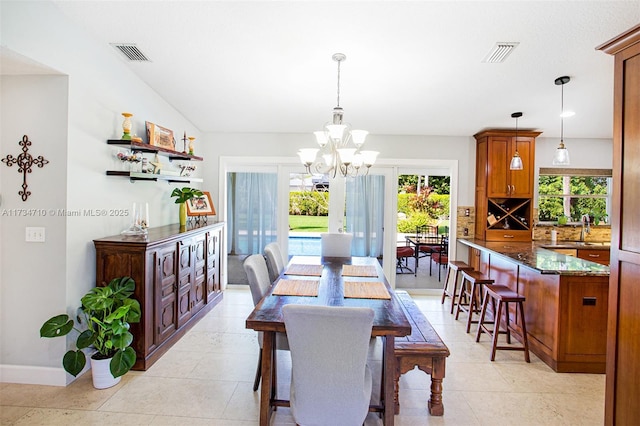 tiled dining space with a healthy amount of sunlight, sink, and an inviting chandelier