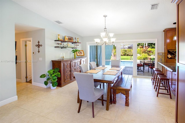 dining area with vaulted ceiling, light tile patterned flooring, and an inviting chandelier