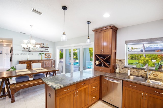 kitchen with stone countertops, pendant lighting, sink, and stainless steel dishwasher