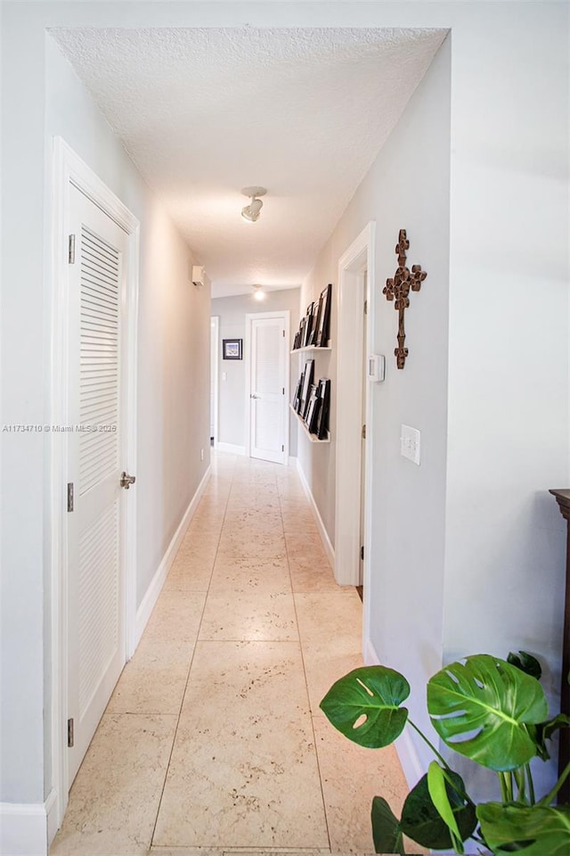 hallway featuring a textured ceiling and light tile patterned floors