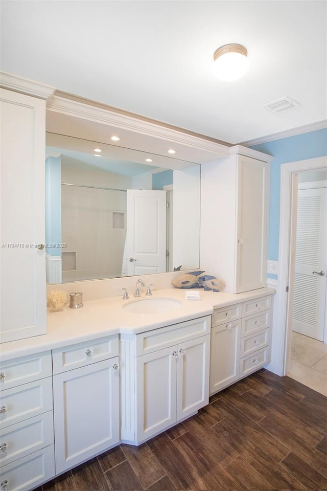 bathroom with vanity, hardwood / wood-style flooring, and crown molding