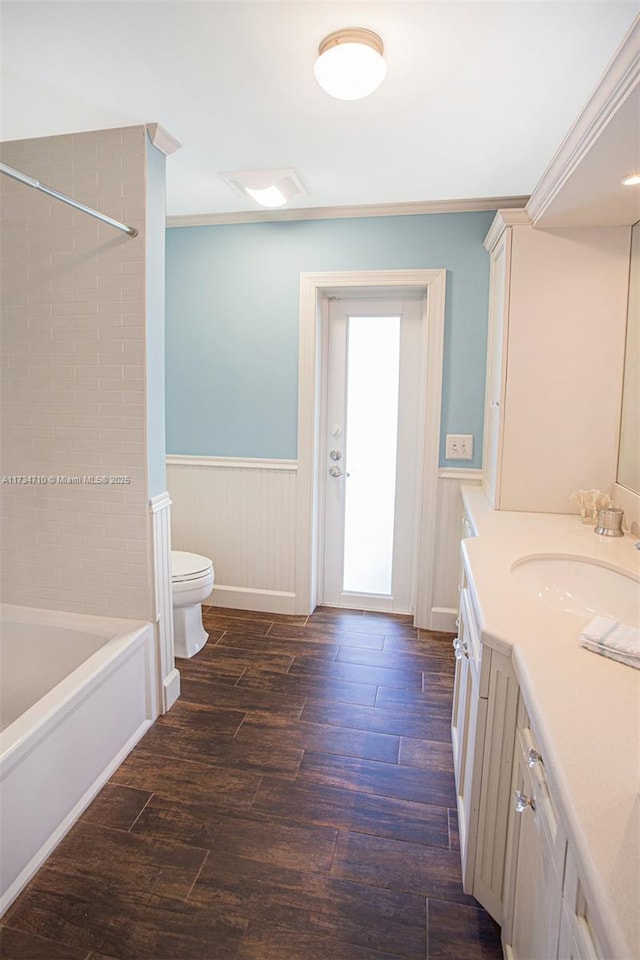 full bathroom featuring tiled shower / bath, hardwood / wood-style flooring, vanity, ornamental molding, and toilet