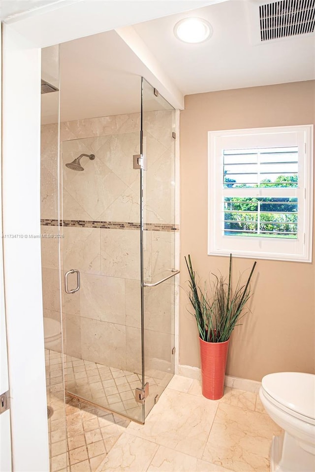 bathroom featuring a shower with shower door and toilet