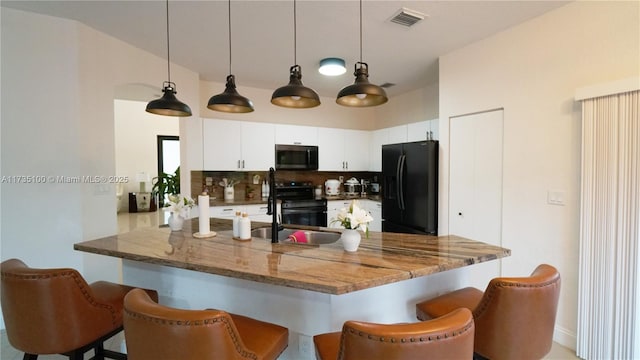 kitchen featuring electric stove, decorative light fixtures, white cabinets, and black fridge