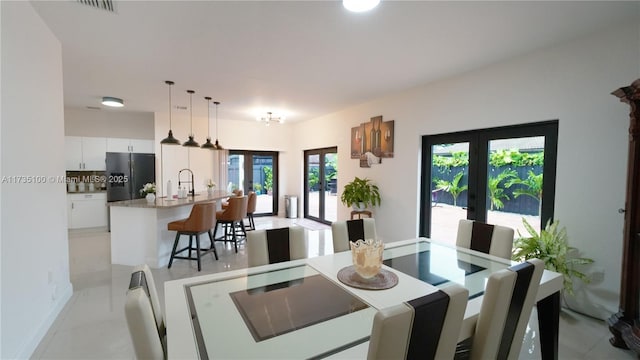 tiled dining space with sink and french doors