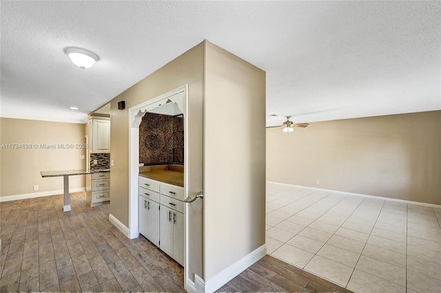 kitchen featuring ceiling fan, decorative backsplash, light hardwood / wood-style flooring, and a textured ceiling