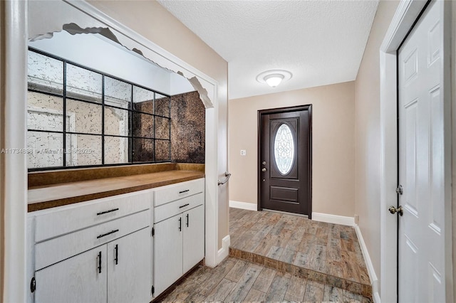 entryway with a textured ceiling and light hardwood / wood-style flooring