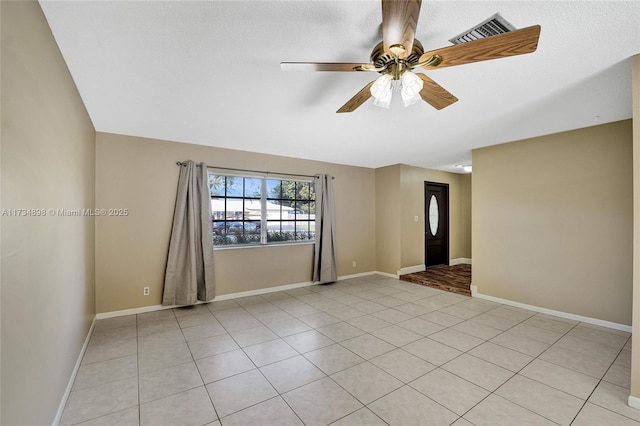 tiled spare room with a textured ceiling and ceiling fan