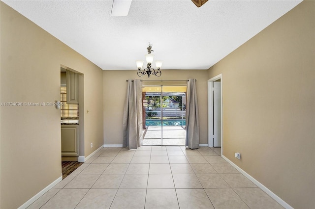 unfurnished dining area featuring an inviting chandelier, a textured ceiling, and light tile patterned floors