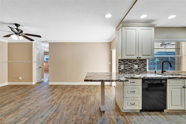 kitchen with tasteful backsplash, sink, black dishwasher, and light wood-type flooring