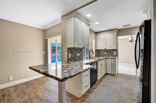 kitchen featuring kitchen peninsula, a kitchen breakfast bar, dark stone counters, decorative backsplash, and black appliances