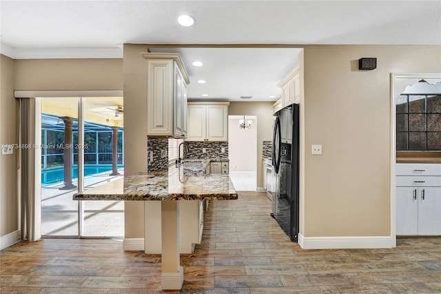 kitchen featuring black refrigerator, plenty of natural light, kitchen peninsula, and a breakfast bar