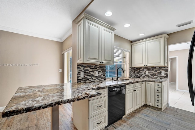 kitchen with sink, black dishwasher, dark stone counters, kitchen peninsula, and light hardwood / wood-style flooring