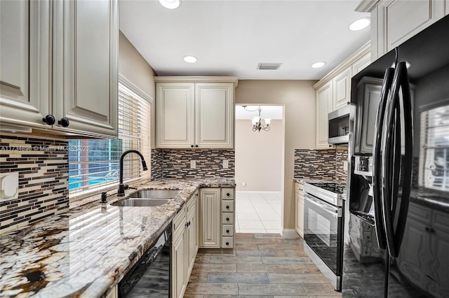 kitchen with light stone countertops, sink, cream cabinets, and black appliances