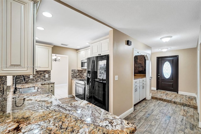 kitchen with sink, decorative backsplash, stainless steel appliances, light stone countertops, and light wood-type flooring