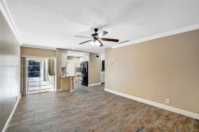 unfurnished living room with ceiling fan, ornamental molding, hardwood / wood-style floors, and a textured ceiling