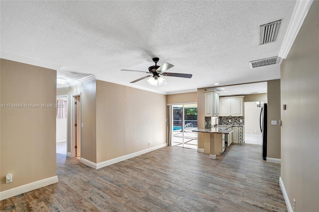 kitchen featuring crown molding, ceiling fan, backsplash, and light wood-type flooring