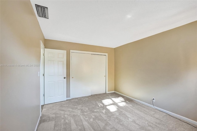 unfurnished bedroom featuring light carpet and a closet