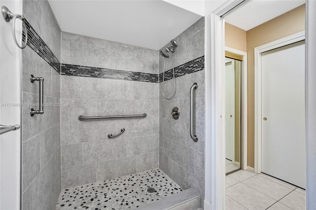 bathroom featuring tile patterned flooring and tiled shower