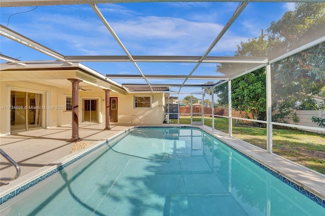 view of swimming pool with ceiling fan, a patio, and glass enclosure