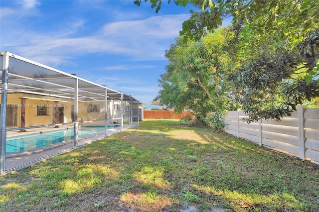 view of yard featuring a fenced in pool and glass enclosure