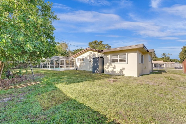 rear view of house with a yard, a swimming pool, and glass enclosure