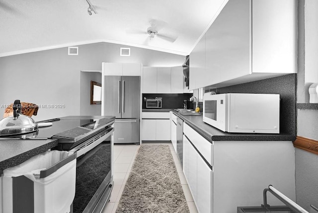 kitchen featuring lofted ceiling, sink, white cabinetry, light tile patterned floors, and stainless steel appliances