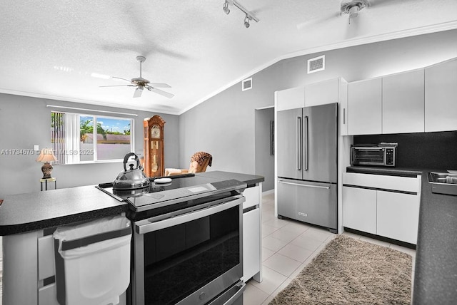 kitchen with stainless steel appliances, ornamental molding, a textured ceiling, white cabinets, and vaulted ceiling