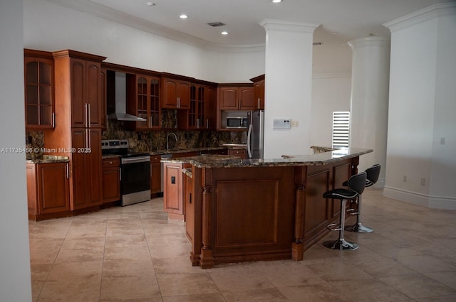 kitchen with appliances with stainless steel finishes, sink, dark stone countertops, a center island, and wall chimney exhaust hood