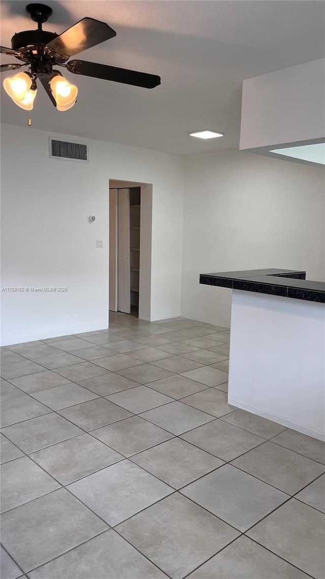 tiled empty room featuring ceiling fan