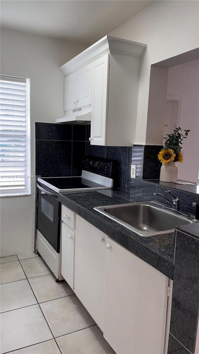 kitchen featuring sink, white cabinetry, light tile patterned floors, range with electric cooktop, and decorative backsplash