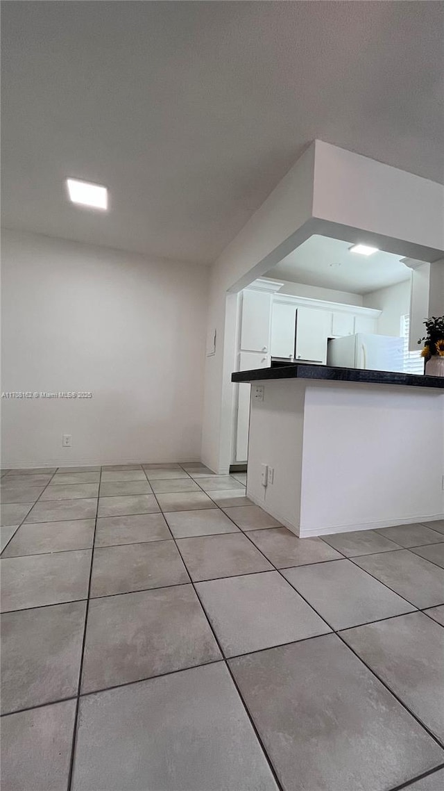 kitchen featuring light tile patterned floors, white fridge, and white cabinets