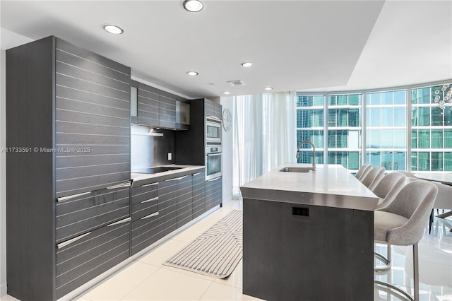 kitchen featuring appliances with stainless steel finishes, a kitchen island with sink, sink, and light tile patterned floors