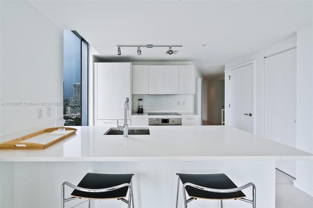 kitchen with sink, a breakfast bar area, oven, and black electric stovetop