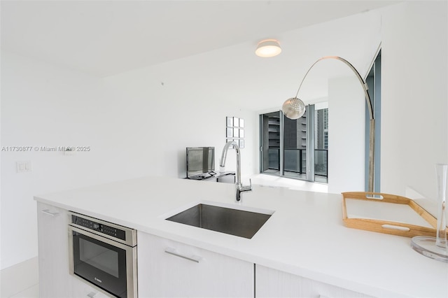 kitchen featuring sink, oven, and white cabinets