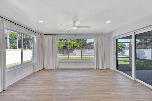 empty room with ceiling fan and light hardwood / wood-style flooring