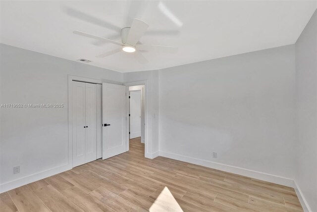 unfurnished bedroom featuring ceiling fan, a closet, and light hardwood / wood-style flooring