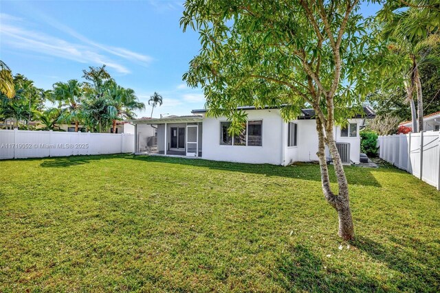 rear view of property featuring central AC unit and a lawn