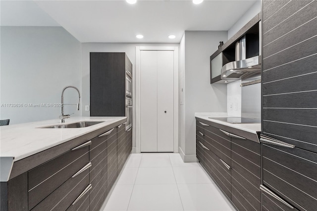 kitchen with black electric cooktop, sink, light tile patterned floors, and oven