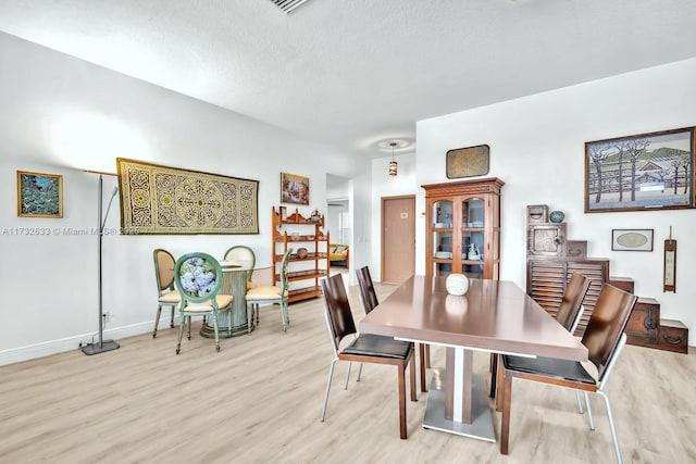 dining room featuring light hardwood / wood-style floors and a textured ceiling