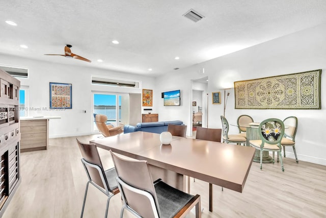 dining area featuring ceiling fan, light hardwood / wood-style floors, and a textured ceiling