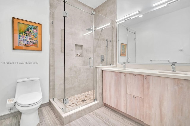 bathroom with wood-type flooring, a shower with shower door, vanity, and toilet