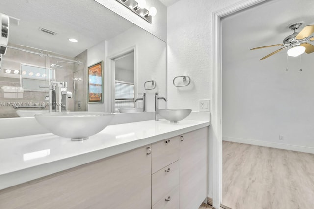 bathroom with ceiling fan, hardwood / wood-style floors, vanity, a textured ceiling, and walk in shower