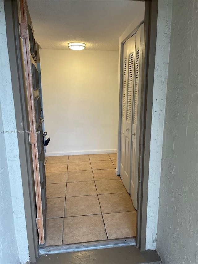 corridor featuring light tile patterned floors and a textured ceiling