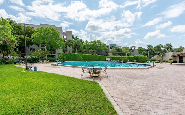 view of pool with a patio area and a lawn