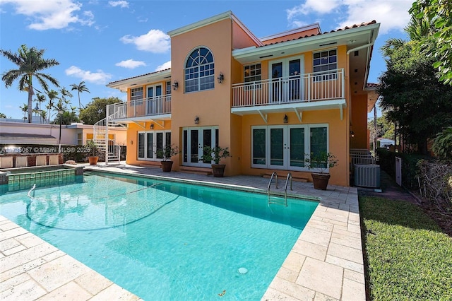 view of swimming pool with french doors, an in ground hot tub, a patio area, and cooling unit