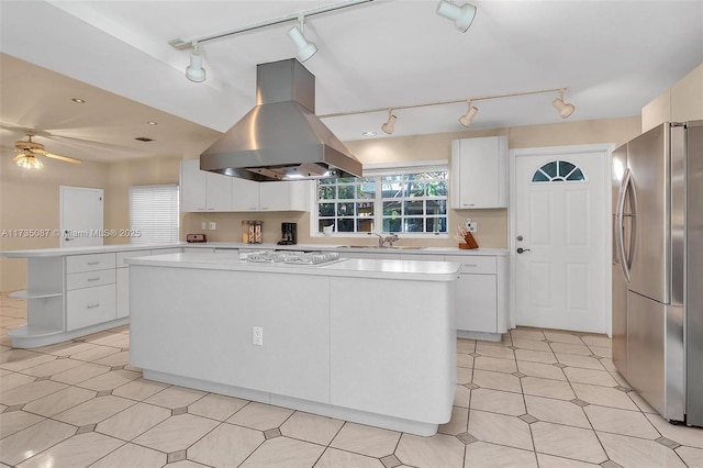 kitchen featuring sink, white cabinetry, island range hood, a center island, and stainless steel fridge