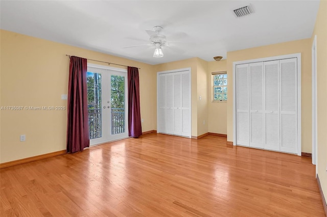 unfurnished bedroom with ceiling fan, access to exterior, light hardwood / wood-style floors, two closets, and french doors