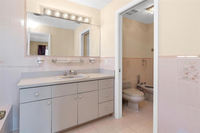 bathroom featuring a bidet, tile walls, vanity, tile patterned floors, and toilet