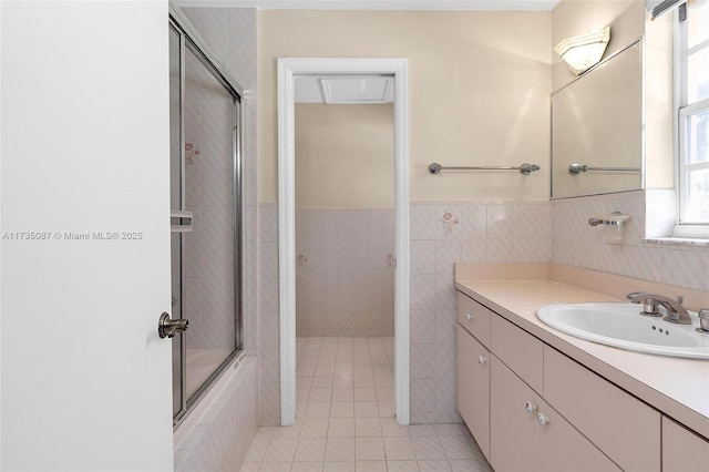 bathroom with tile patterned flooring, bath / shower combo with glass door, tile walls, and vanity